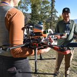 Photo of conference sponsor with an attendee, and a drone, at the 2024 Colorado Wildland Fire Conference